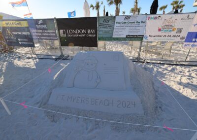 Sand sculpture shaped like a holiday postcard with a snowman and “Merry Christmas” text.