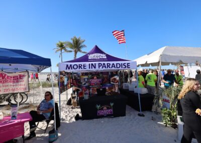 Colorful casino and ferry promo booths set up on a sunny beach with visitors.
