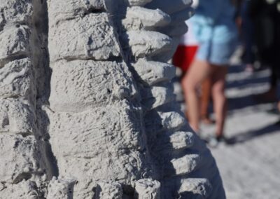 Detailed sand sculpture resembling layered ribs with people standing nearby.