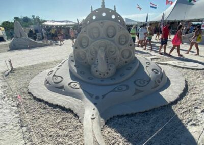 Large manta ray–shaped sand sculpture with ornate circular patterns at an outdoor competition.