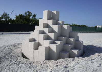 Stepped pyramid of stacked rectangular sand blocks with clean edges under a clear sky.