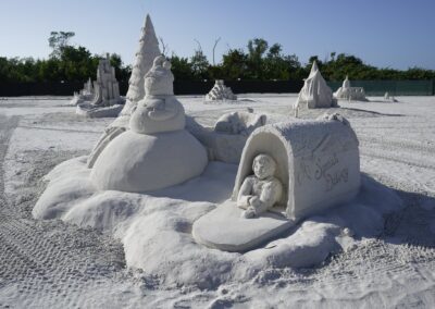Sand sculpture of a snowman, Christmas tree, and “Special Delivery” mailbox at a beach festival.