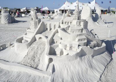 Detailed multi‑tower sand castle with arches and stairways at a beach sand sculpting event.