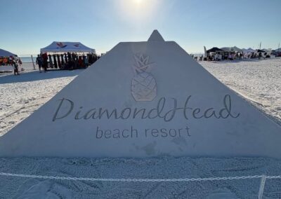 “Large sand pyramid with a carved pineapple and ‘DiamondHead Beach Resort’ text under a bright blue sky.”