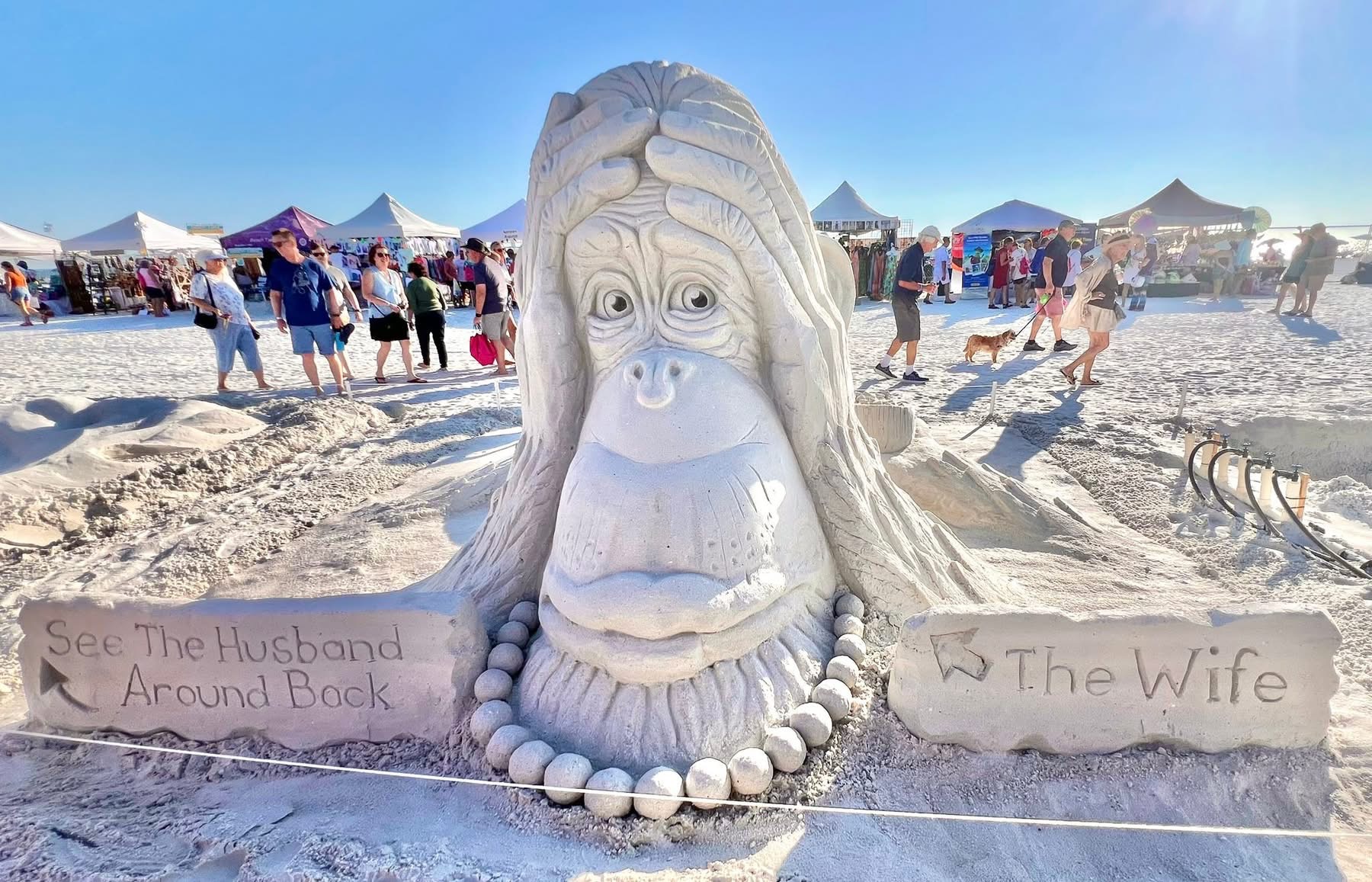 IMG_0877 Humorous sand sculpture of a wide-eyed character with signs pointing to “The Wife” and “Husband Around Back.”