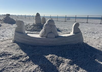 Sand sculpture of a Viking seated in a longboat with carved wave patterns and detailed helmet and beard.