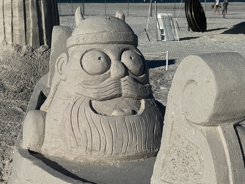 Sand sculpture of a cartoon-style Viking head with a horned helmet, large eyes, and a long beard.
